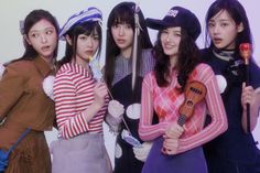 four young women are dressed in costumes and holding musical instruments while posing for the camera