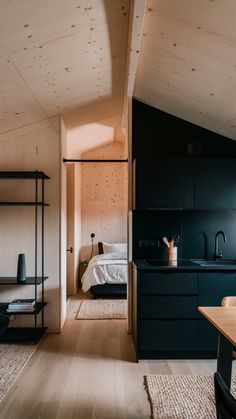 an open kitchen and living room with wood flooring, black cabinets and white walls