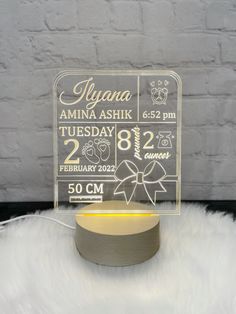 an acrylic sign on top of a white furnishing next to a brick wall