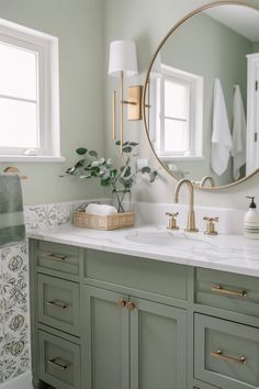 a bathroom with green cabinets and a round mirror