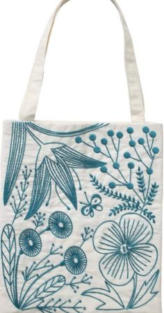 a blue and white tote bag with flowers on the front, in an embroidered design