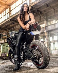 a woman sitting on top of a motorcycle in an old building with lots of windows