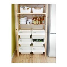 an organized pantry with white containers and drinks on the bottom shelf next to a refrigerator