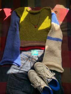 a pair of sneakers, sweater and jeans are sitting on a plaid blanket next to shoes