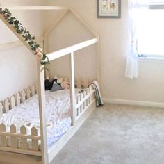 a bedroom with a white bed frame and flowers on the top of it, in front of a window