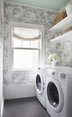 a washer and dryer in a bathroom with floral wallpaper on the walls