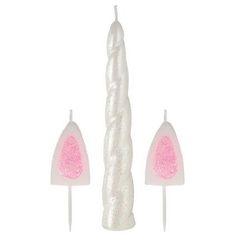 three candles with pink and white decorations on top of each candle, one in the shape of a cone