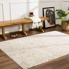 a wooden bench sitting next to a white rug on top of a hard wood floor