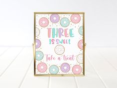 there is a sign that says, three is sweet take a treat with donuts on it