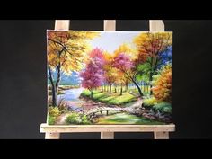 an easel with a painting on it that is displaying a colorful forest and stream