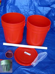 two red plastic buckets with white handles and lids on a blue tarp