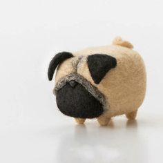 a small stuffed pug dog is shown on a white surface with its head turned to the side