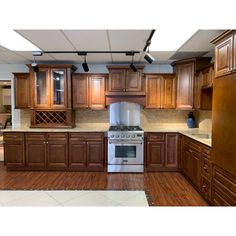 an empty kitchen with wooden cabinets and stainless steel stove top oven in the middle of the room