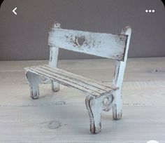 an old white wooden bench sitting on top of a hard wood floor next to a gray wall