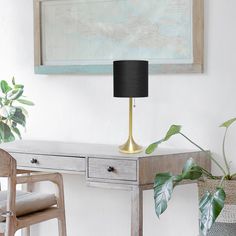 a desk with a lamp, chair and potted plant