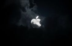 an apple logo is seen through the dark clouds