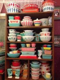 a shelf filled with lots of different colored bowls and plates on top of each other