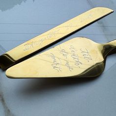 two gold scissors with writing on them sitting on the hood of a car in front of a window