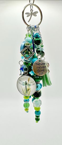 a keychain that has some glass beads hanging from it's side and the words never give up on it