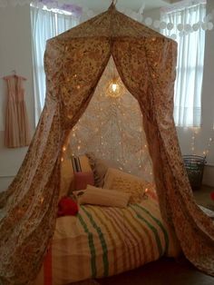 a canopy bed with lights on it in a bedroom next to a curtained window