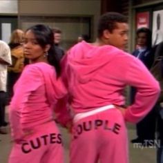 two people in pink sweat suits with the words cuties couple on their back, standing next to each other