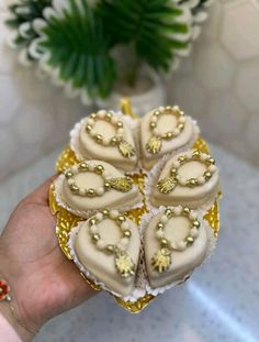 a person holding some kind of heart shaped cake in their hand with gold and white decorations on it