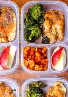 four plastic containers filled with food on top of a wooden table next to an apple and broccoli