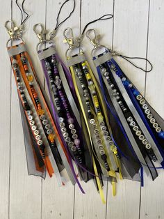 several different colored lanyards with metal tags attached to them on a white wooden surface