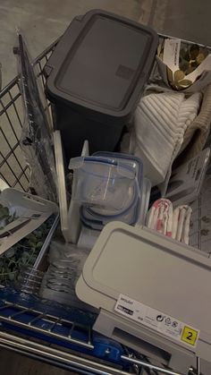 an empty shopping cart filled with items on top of a floor next to a trash can