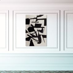 an abstract black and white painting hangs on the wall