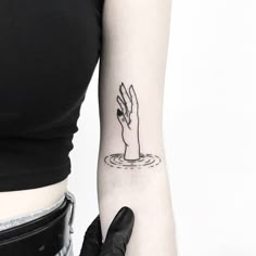 a woman's arm with a tattoo on it and a hand in the water