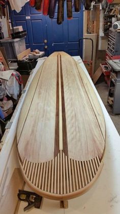 a wooden surfboard sitting on top of a table in a room filled with tools