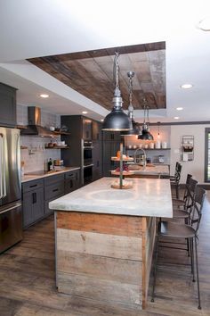 a large kitchen with an island in the middle and stainless steel appliances on both sides