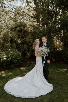 a bride and groom standing in the grass