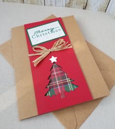 a christmas card with a plaid tree on it, tied up to brown envelopes