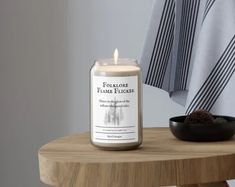 a candle sitting on top of a wooden table next to a bowl and towel rack