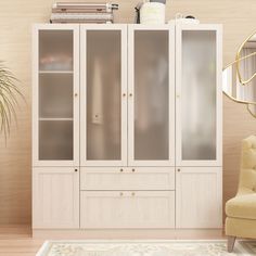 a white cabinet with glass doors and drawers in a living room next to a chair