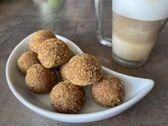 a white plate topped with balls of food next to a glass of milk on top of a table