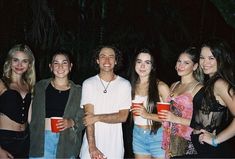 a group of young people standing next to each other holding red cups in their hands