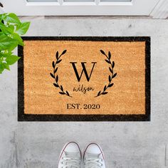 a door mat with the letter v on it next to a pair of white shoes