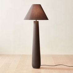 a lamp that is on top of a wooden floor in front of a white wall