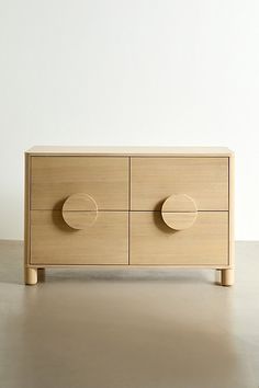 a wooden dresser with three drawers and two knobs