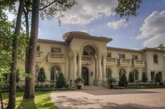 a large white house surrounded by trees and grass