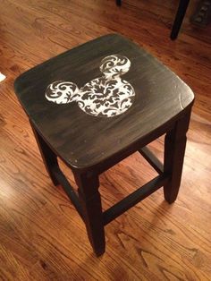 a small wooden stool with a mickey mouse painted on the top and bottom part of it