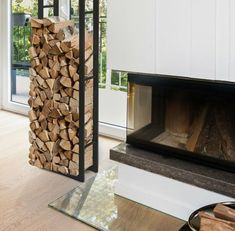 a fire place with wood stacked in front of it and a glass table next to it