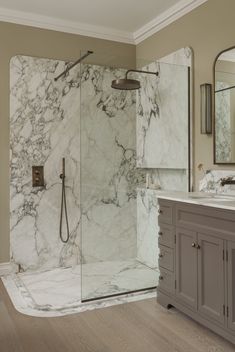 a bathroom with marbled walls and flooring is pictured in this image, there are two mirrors on the wall next to the shower