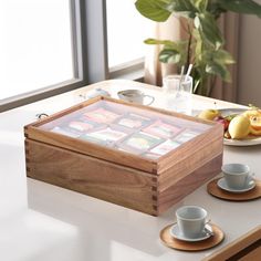 a wooden box sitting on top of a table next to two cups and saucers