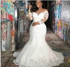 a woman in a white wedding dress standing in an alley with graffiti on the walls