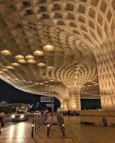 the interior of an airport at night with people walking around and cars parked in front of it