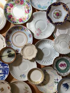 an array of china plates and saucers are arranged on a table top with one plate in the middle